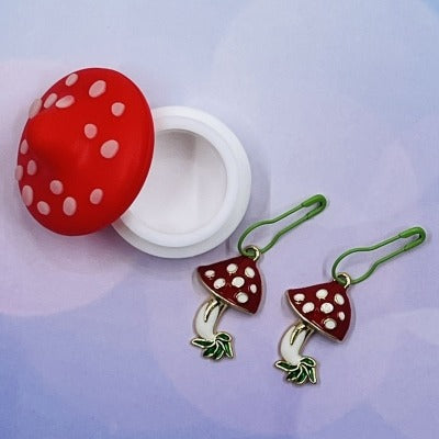 Mini silicone mushroom-shaped jar with two enamel mushroom-shaped knitting and crochet stitch markers